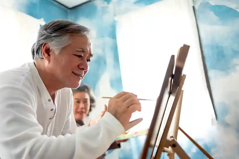 Senior man painting in a workshop at a retirement community.